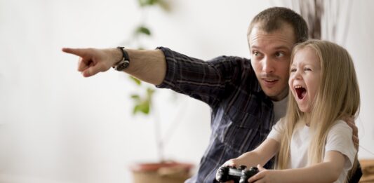 Homem ensinando a filha como aprender inglês com videogames