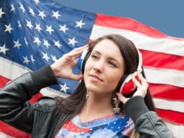 Sua meta é aprender inglês em 2025? Veja 13 dicas para tornar isso realidade! Menina com o seu fone de ouvido e a bandeira dos EUA de fundo representando a Sua meta é aprender inglês em 2025. Veja 13 dicas para tornar isso realidade!