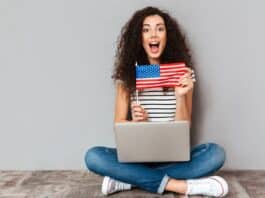 Idiomas e Carreira: Por que aprender inglês pode abrir portas mulher sentada no chão com notebook no colo mostrando bandeira dos Estados Unidos